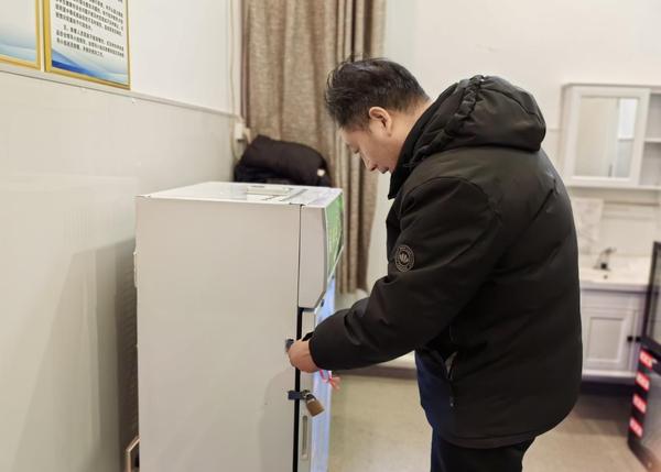 4郑州市第七初级中学东校区校长王海勤对餐食留样柜进行检查